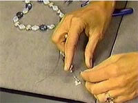 Hands stringing beads on a workstation